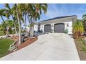 Landscaped front yard with palm trees and a two-car garage at 1454 Kiwi Ct, Punta Gorda, FL 33950