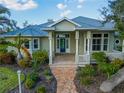 Charming single-story home with lush landscaping, covered porch, and blue front door at 27320 Egret Pl, Punta Gorda, FL 33983