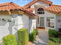Close up of the front entrance of the home, showing stucco walls and a lovely, well-manicured garden at 1164 Harbor Town Way, Venice, FL 34292