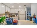 A bright kitchen featuring white appliances and ample counter space with an opening to another room at 19505 Quesada Ave # O104, Port Charlotte, FL 33948