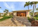 Tan house with metal roof, palm trees, landscaped yard, and paved driveway at 2198 El Cerito Ct, Punta Gorda, FL 33950