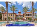 Resort style pool and clubhouse with tropical landscaping and blue tiled water feature at 91 Vivante Blvd # 402/9142, Punta Gorda, FL 33950