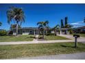 Single-story house with green exterior, palm trees, and a two-car garage at 125 Ott Cir, Port Charlotte, FL 33952