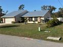 Charming single-story home with blue metal roof, well-maintained landscaping, and attached garage at 1311 Abscott St, Port Charlotte, FL 33952