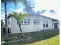 Side view of the house showcasing its light-colored exterior and landscaping at 21157 Midway Blvd, Port Charlotte, FL 33952