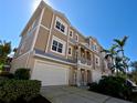 Exterior view of the tan three-story condo building, highlighting its large windows, garage and well-manicured landscaping at 10311 Lands End Cir # 16, Placida, FL 33946