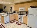 Bright kitchen with wooden cabinets, white appliances, and decorative rugs at 1186 Rio De Janeiro Ave # 106, Punta Gorda, FL 33983