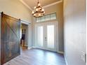 This home features an elegant foyer with grand ceilings, a decorative chandelier, and a modern sliding barn door at 17350 Bayharbor Cir, Port Charlotte, FL 33948