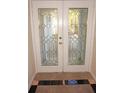 Elegant front doors featuring a decorative glass design, marble tile, and brass hardware at 21535 Edgewater Dr, Port Charlotte, FL 33952