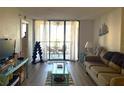 Cozy living room featuring neutral tones, sliding glass doors to screened patio, and laminate flooring at 3006 Caring Way # 409, Port Charlotte, FL 33952