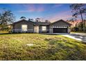 Charming single story house with gray exterior, attached garage, and green lawn at sunset at 4175 Horseshoe Ave, North Port, FL 34286