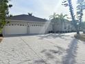 Expansive concrete driveway leading to a three-car garage, complemented by manicured landscaping and palm trees at 1259 Royal Tern Dr, Punta Gorda, FL 33950