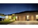 Exterior view of a tan single-Gathering home showing a well-manicured lawn, palm trees, and paved driveway during the evening at 17122 Barcrest Ln, Punta Gorda, FL 33955