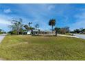 Inviting single-story house with a well-kept lawn, mature trees, and a long driveway leading to a garage at 21192 Knollwood Ave, Port Charlotte, FL 33952