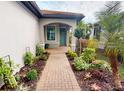 Inviting entrance with a brick path, teal door, and beautiful landscaping creating a warm welcome at 2478 Brassica Dr, North Port, FL 34289