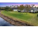 Sprawling backyard with lush green grass and mature trees backs up to a picturesque pond at 2639 Hobblebrush Dr, North Port, FL 34289