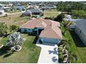 Single-story home with a two-car garage, well-manicured lawn, and palm trees in a quiet neighborhood at 9175 Melody Cir, Port Charlotte, FL 33981