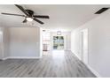 Open-concept living room with wood-look floors, white walls, ceiling fan, and views into the kitchen at 11176 3Rd Ave, Punta Gorda, FL 33955