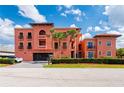 Attractive three-story building with balconies, a red tile roof, mature palm trees and attached garages at 1344 Mediterranean Dr # 121, Punta Gorda, FL 33950