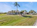 Inviting single-story home with a large lawn and an attached two-car garage, complemented by mature palm trees at 27566 Tierra Del Fuego Cir, Punta Gorda, FL 33983