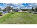 Spacious grassy backyard featuring a covered porch, neighboring homes, and blue skies at 3120 Wisteria Pl, Punta Gorda, FL 33950