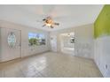 Bright living room with tile floors, ceiling fan and natural light with view to the outdoors through a large window at 3615 Sleepy Hollow Ln, Punta Gorda, FL 33950