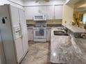 Well-lit kitchen with granite countertops, white appliances, and a stainless steel sink at 4000 Bal Harbor Blvd # 527, Punta Gorda, FL 33950