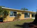 Side view of a yellow home featuring bright double-pane windows and lush landscaping at 21938 Catherine Ave, Port Charlotte, FL 33952