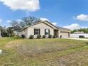 Well-manicured lawn and landscaping surround this beige single-Gathering home with an attached two-car garage at 2822 Logsdon St, North Port, FL 34287