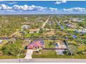 Expansive aerial shot of a community featuring mature trees, water features, and a home with a metal roof at 8230 Agate St, Port Charlotte, FL 33981