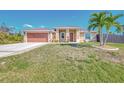 Inviting single-story home showcasing a metal roof, lush lawn, and a spacious driveway leading to a two-car garage at 8230 Agate St, Port Charlotte, FL 33981