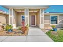 Close-up of a home's entryway featuring decorative columns, a brown front door, and beautiful landscaping at 8230 Agate St, Port Charlotte, FL 33981