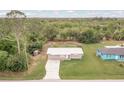 Aerial view of a charming home with a long driveway, surrounded by lush greenery and trees at 11369 1St Ave, Punta Gorda, FL 33955
