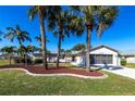 Well-maintained single-story home featuring mature landscaping, a two-car garage, and a metal roof at 483 Corrientes Cir, Punta Gorda, FL 33983