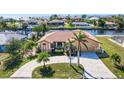 Waterfront home featuring a tile roof, circle driveway, and tropical landscaping at 105 Sinclair Se St, Port Charlotte, FL 33952