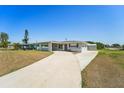 Inviting single-story home featuring an expansive driveway and a charming covered porch at 556 Lowell Nw Ave, Port Charlotte, FL 33952