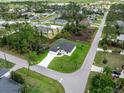 An aerial view of a single-story home featuring a white exterior, surrounded by lush greenery and a well-kept lawn at 1022 S Lavina St, North Port, FL 34286