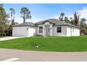 A modern single-Gathering home showcases a white exterior, attached garage, and a lush green lawn at 1022 S Lavina St, North Port, FL 34286