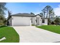 A well-maintained, single-story home boasts a white exterior, two-car garage, and a spacious concrete driveway at 1022 S Lavina St, North Port, FL 34286