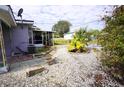 Backyard featuring a stone area with a garden, tropical plants, and a screened-in porch at 21422 Mallory Ave, Port Charlotte, FL 33952