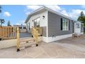 Single-wide home with gray and white exterior, wooden deck, and stone patio at 6287 Oriole Blvd, Englewood, FL 34224