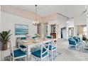 Bright dining room featuring a white table with blue chairs and a lovely seascape painting at 523 Foxwood Blvd, Englewood, FL 34223