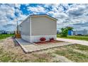 Rear view of tan mobile home with landscaping at 1391 Flamingo Dr, Englewood, FL 34224