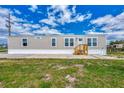 Tan mobile home with wood stairs and grassy yard at 1391 Flamingo Dr, Englewood, FL 34224