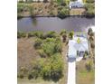Aerial view showing property with a canal waterfront, pool, and landscaping, plus additional vacant lot at 15001 Appleton Blvd, Port Charlotte, FL 33981