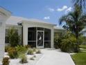 Charming home exterior with lush landscaping and a screened-in porch featuring a decorative sailboat door at 15001 Appleton Blvd, Port Charlotte, FL 33981