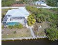 Aerial view showcasing a screened-in pool, patio, and waterfront access with a canal behind the home at 15001 Appleton Blvd, Port Charlotte, FL 33981