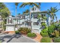 Light teal three-story house with palm trees, brick walkway, and attached two-car garage at 13310 Anglers Way, Placida, FL 33946