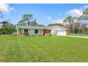 Ranch-style home with green roof, white exterior, and large yard at 1115 Larchmont Dr, Englewood, FL 34223