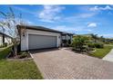 Brick paver driveway leads to a modern home with gray garage door and landscaped yard at 1337 Sorrell Way, North Port, FL 34289